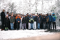 Etwa 35 Jugendliche stehen gemeinsam als Gruppe in Winterkleidung im verschneiten Wald.